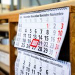 Papierkalender mit Monatsansicht in einer Werkstatt; ein Tag ist rot markiert